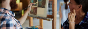 teacher looking at painting of one of her students in art-studio