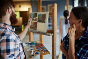 teacher looking at painting of one of her students in art-studio